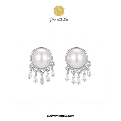 Radiant Mini Silver Pearl Stud Earring - #Radiant Mini Silver Pearl Stud EarringJewelryGlow With NazGlow With NazE087A pair of silver-toned dangle earrings featuring a large white pearl in a round bezel setting, with three clear crystal drops hanging below. The brand logo 'Glow with Naz' is displayed at the top, and the website 'GLOWWITHNAZ.#