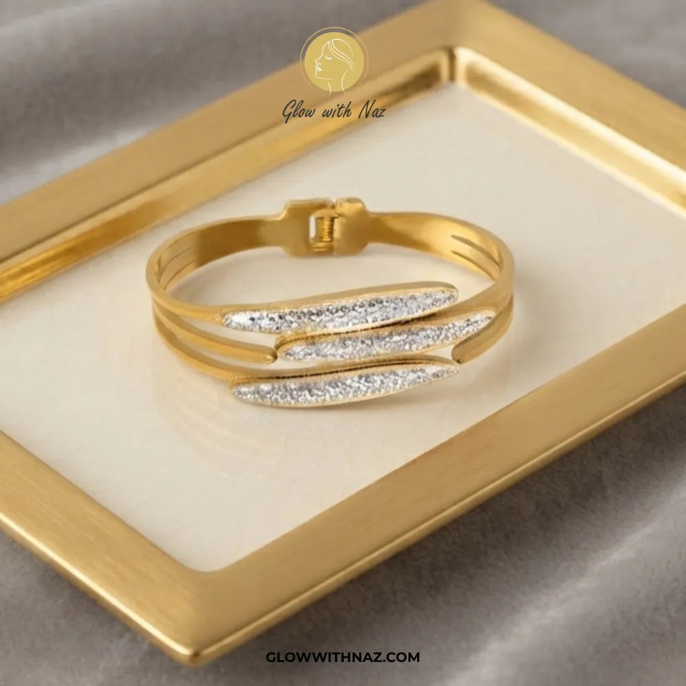 Gold triple fish crystal cuff bracelet worn on model wrist against blue velvet background by Glow With Naz