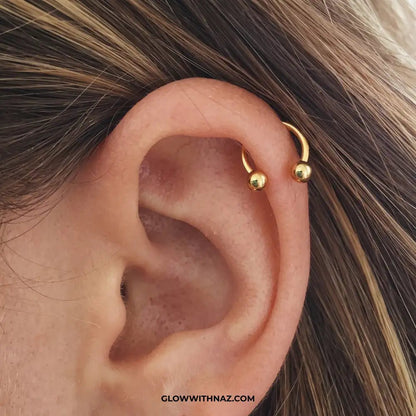 Stainless Steel Horseshoe 8.5 mm C Nose Ring & Helix Ear Piercing Jewelry - Stainless Steel Horseshoe 8.5 mm C Nose Ring & Helix Ear Piercing JewelryJewelryGlow With NazGlow With NazNR004A close-up of a person's ear featuring a small gold hoop piercing on the upper helix, with strands of brown hair visible around it. nose ring, helix piercing jewelry, cartilage earring, horseshoe piercing, septum ring, stainless steel jewelry, body jewelry, hypoallergenic nose ring, gold nose ring, helix hoop, t