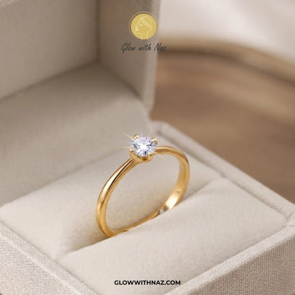 Timeless 4 Grip Diamond Ring for Women - Timeless 4 Grip Diamond Ring for WomenJewelryGlow With NazGlow With NazA gold solitaire ring with a clear round gemstone displayed inside an open beige jewelry box. The brand name 'Glow with Naz' is visible as a watermark at the top and in the URL at the bottom. ring, girls rings, rings for girls, rings simple, simple rings, stainless steel jewelry, jewellery set, aesthetic jewelry, simple jewellery, chain, jewelry, artificial jewellery