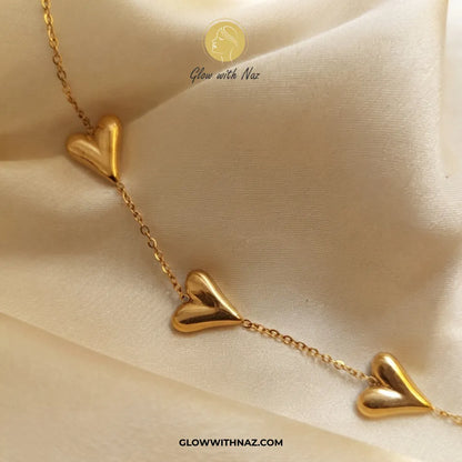 Trio puffed balloon heart bracelet in gold laid on cream silk fabric by Glow With Naz