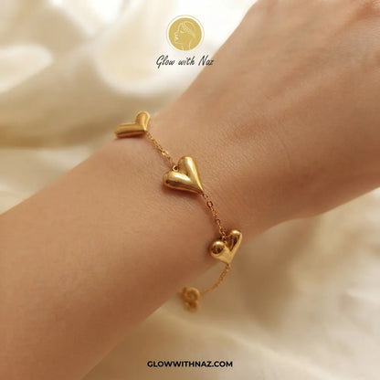 Trio puffed balloon heart gold bracelet worn on model wrist by Glow With Naz