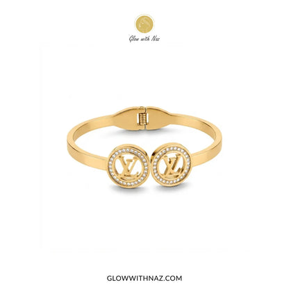 Gold twin LV medallion crystal handcuff bangle flat lay view by Glow With Naz